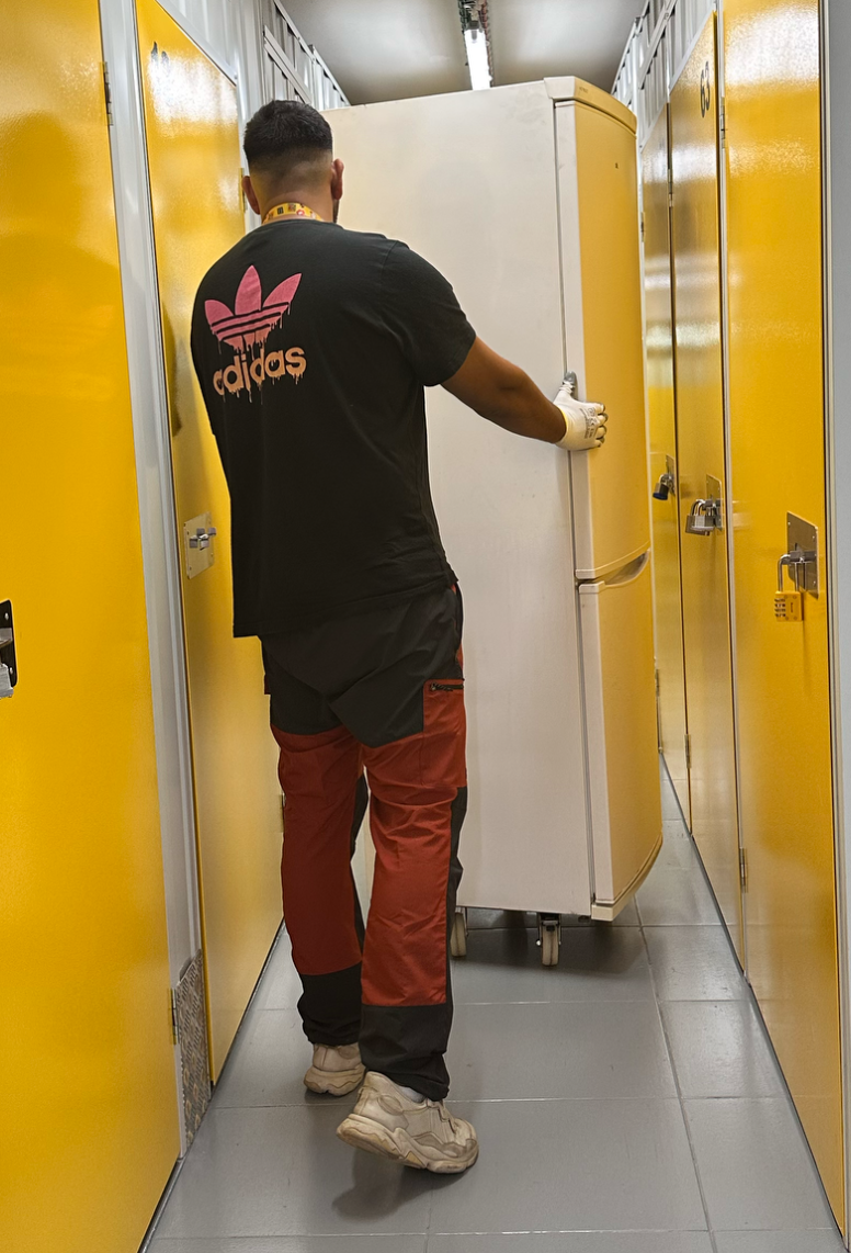 Hombre con uniforme de trabajo frente a electrodomésticos usados para servicio de recogida y reciclaje en domicilio